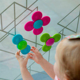 Enfant qui joue avec les toupies sensorielles Squigz Tourbillonnant sur une vitre